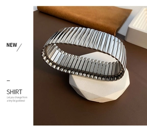 Macro detail of silver-toned ribbed elastic cufflink on a minimalist stone display