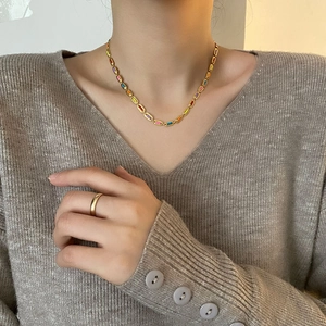 Colorful titanium steel necklace with minimalist gold ring on a knit sweater model