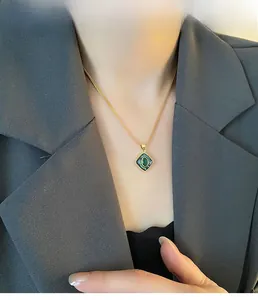 Close-up of vintage gold necklace with square green gemstone pendant on model