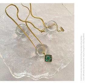 Detailed macro view of a gold snake chain necklace with a green abalone shell pendant