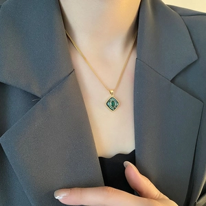 Vintage gold diamond pendant necklace with green shell inlay on a female model