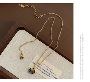 Detailed view of vintage gold lock pendant with blue shell inlay on luxury display tray