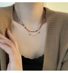 Détail d'un collier double rang en titane avec perles colorées et breloques dorées rondes