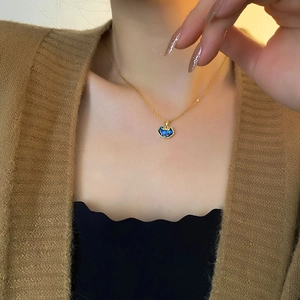 Elegant gold lock necklace with iridescent blue abalone shell pendant on a model