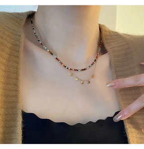 Détail du collier double rang avec perles colorées et pendentifs disques dorés