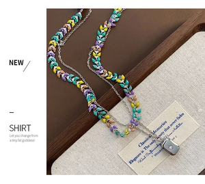 Détail macro d'un collier double rang en titane avec charmes émaillés colorés et zircon