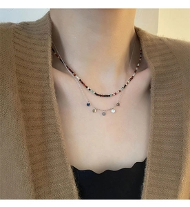 Détail de perles colorées et d'un collier argenté à deux rangs avec petits pendentifs