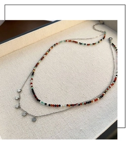 Détail du collier double rang en titane avec perles colorées et pendentifs disques