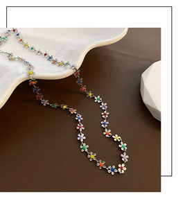 Vue détaillée du collier à fleurs colorées en émail sur un plateau en céramique