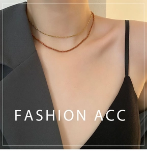 Close-up of layered orange garnet beaded necklace and gold twisted chain on model