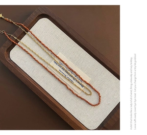 Close-up of double-layered necklace with gold twist chain and faceted garnet beads