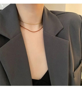Close-up of double-layer orange garnet necklace worn with a gray textured blazer