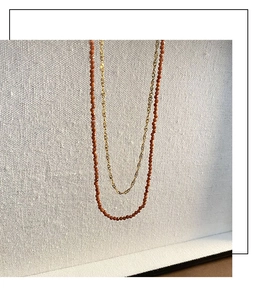 Detail of double-layer necklace with golden chain and gradient orange garnet stone beads