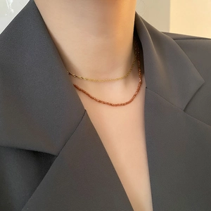 Minimalist double-layered necklace featuring gold chain and garnet beads on a model