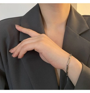 Close-up of minimalist silver rectangular link chain bracelet worn on a female wrist