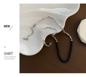 Dettaglio della collana con perle argentate e nere, chiusura a moschettone e catenina