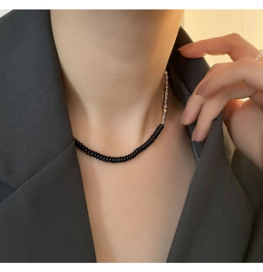 Dettaglio della collana minimalista con perline nere e catena d'argento sul modello
