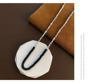 Dettaglio della collana con perle nere e catena a maglie argentate geometriche