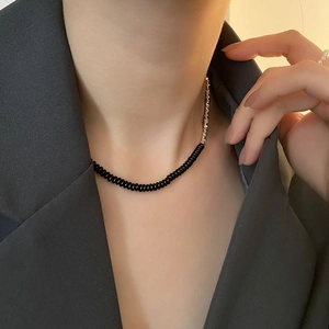 Collana girocollo minimalista con perline argento e nere indossata su un blazer