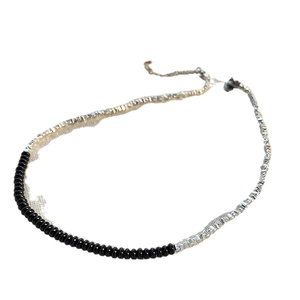 Collana girocollo asimmetrica con perline nere ed elementi quadrati argento su sfondo bianco