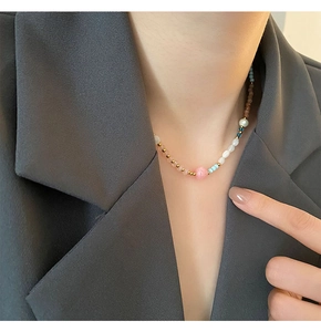 Detail of beaded necklace with strawberry crystal and pearls on a model wearing a blazer