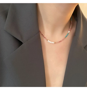 Close-up of pastel beaded necklace with pearls and gold accents on a model's collarbone