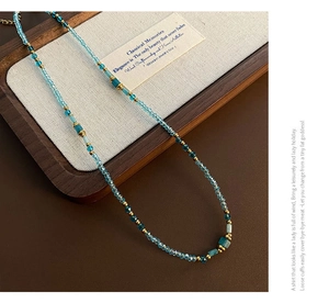 Détail macro du collier artisanal avec perles de cristal bleu et pierre naturelle verte