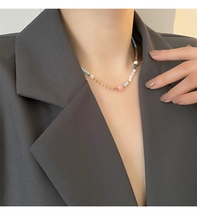 Detail view of strawberry quartz necklace with pastel beads on a grey blazer suit