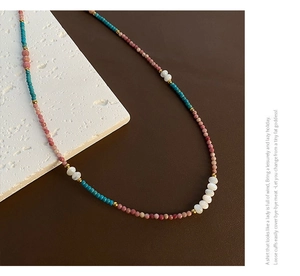 Close-up of pink and turquoise beaded necklace with golden spacers on textured background