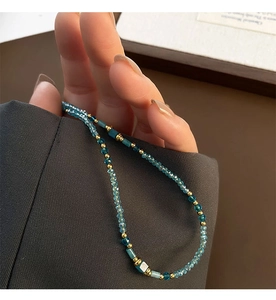 Détail du collier de pierres naturelles avec cristaux bleus et touches dorées sur costume