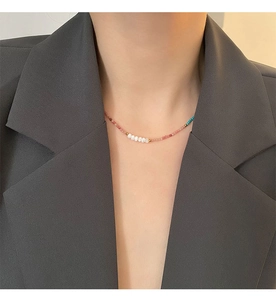 Close-up of elegant pink stone necklace with white pearls on a stylish model