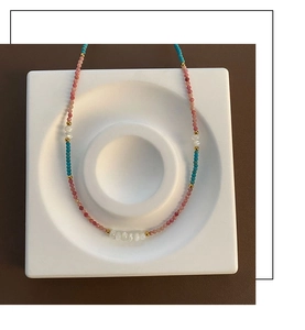 Detail of bohemian beaded necklace with pink, blue, and white stones and gold accents