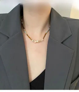 Detail of handmade beaded necklace with freshwater pearls and metallic accents on model