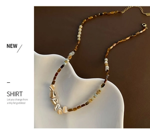 Detail of beaded necklace with tiger eye stones, blue beads, and shell on a ceramic plate