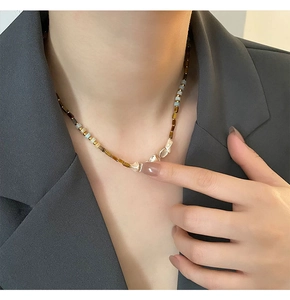 Detail of beaded necklace with brown square beads and irregular natural pearls on a blazer