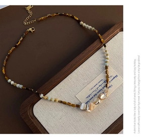 Macro shot of tiger eye beads and natural shell pendants on a handmade boho necklace