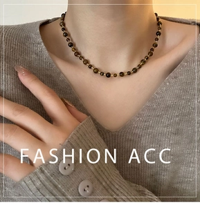 Close-up of handmade beaded tiger eye stone necklace worn on a grey V-neck sweater