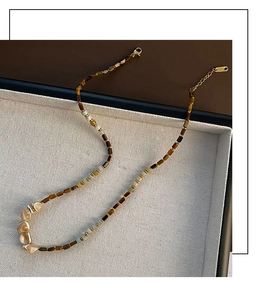 Detail of vintage handmade beaded necklace with brown stones and shell beads in a tray