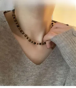 Detail of beaded choker necklace with tiger eye stones and golden beads on a model