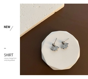 Macro detail of silver lotus petal earrings on geometric stone with luxury texture