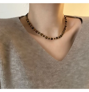 Detailed close-up of handmade tiger eye beaded necklace on a model with warm tones