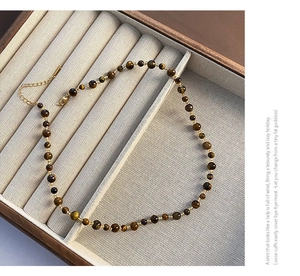 Detail of beaded necklace featuring tiger eye stones, gold spacers, and lobster clasp
