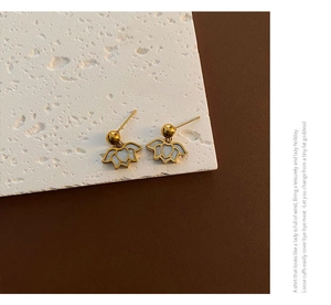 Detailed close-up of gold lotus earrings with white mother of pearl inlay on stone