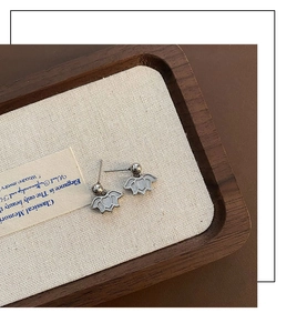 Detail of silver lotus drop earrings with small bead accent on a vintage tray