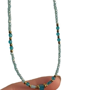 Collier artisanal en perles avec pierres naturelles bleues et accents dorés sur fond blanc