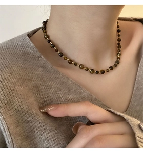 Close-up of tiger eye stone beaded necklace with gold spacers on a beige sweater