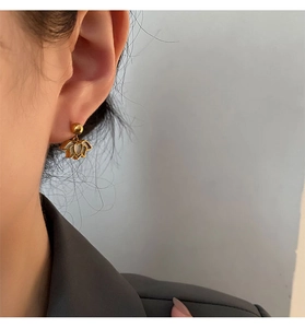 Detail of a lotus flower gold stud earring with white petal inlay on a model