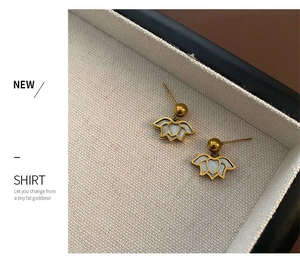 Detail of elegant gold lotus drop earrings with white shell inlay on a jewelry box