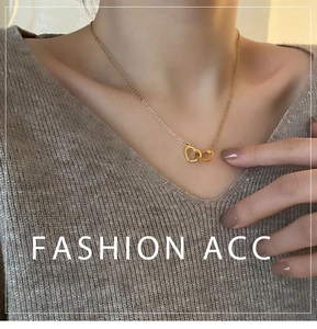 Close-up of interlocking double heart gold necklace worn over a brown sweater
