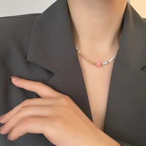 Titanium steel necklace with strawberry quartz and pearls worn on a grey suit jacket